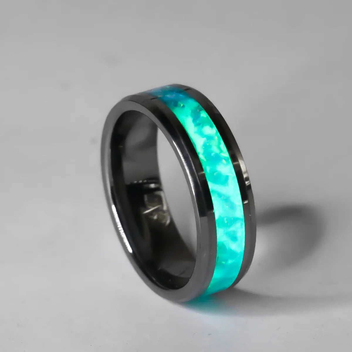 Black Ring with turquoise and glow inlay on a gray background