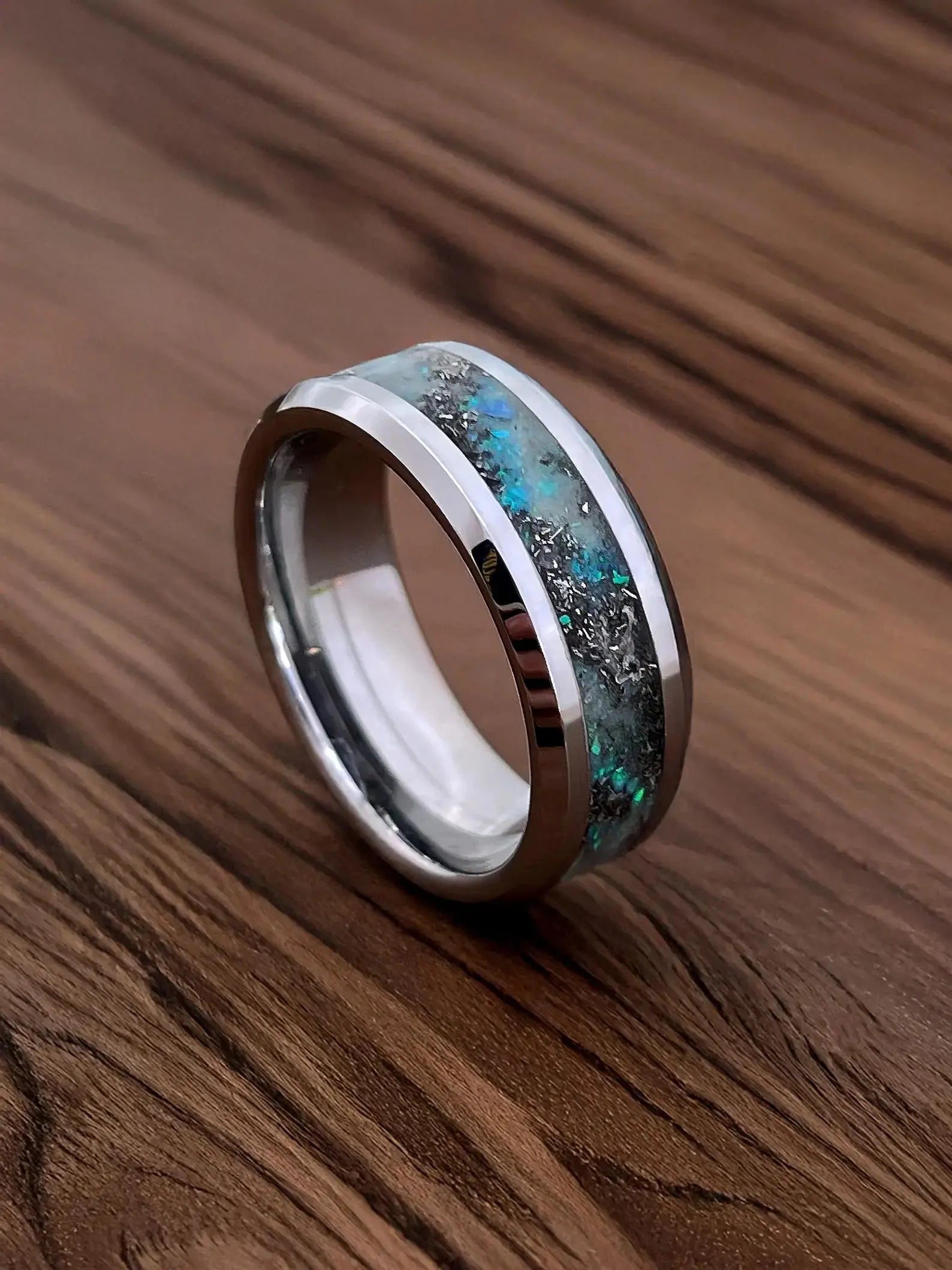 Silver ring with a blue and green inlay on a wooden surface
