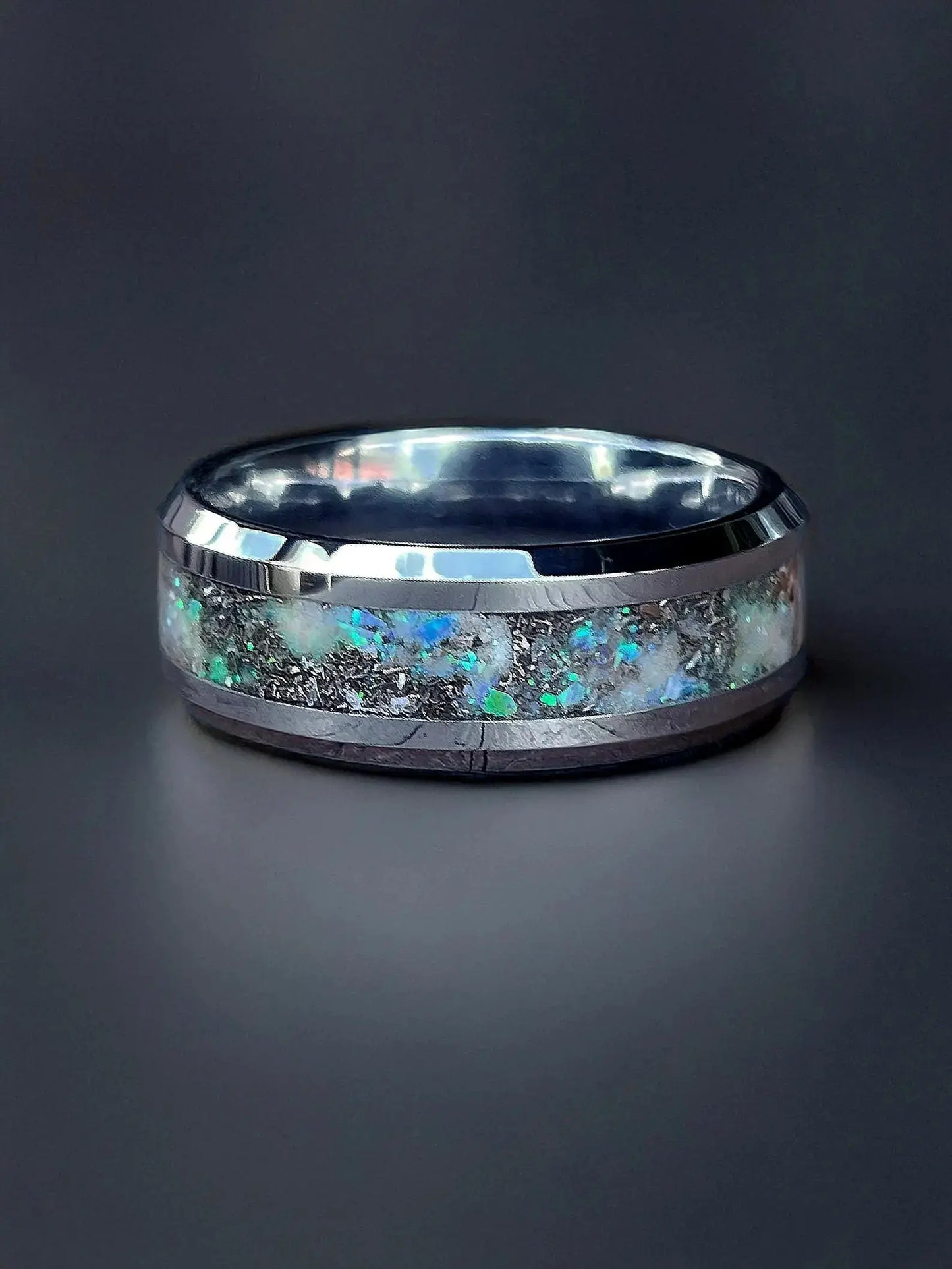 Silver ring with embedded gemstones on a dark background